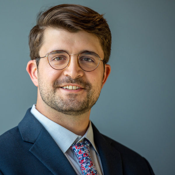 Portrait of Matthew Verdillo in a suit and floral tie.